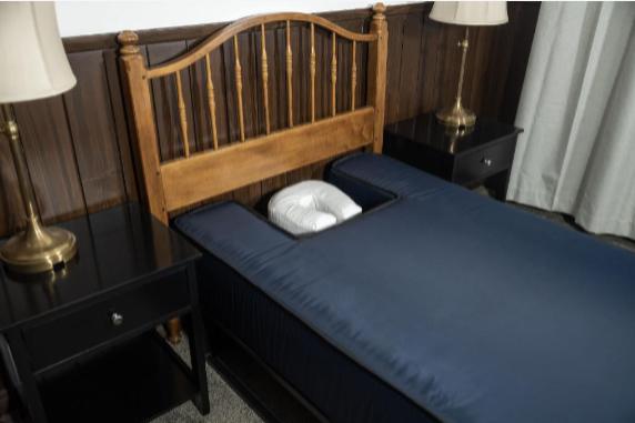 Pure Prone Sleep mattress with navy DWR fabric cover, wooden headboard and brass lamps in bedroom setting
